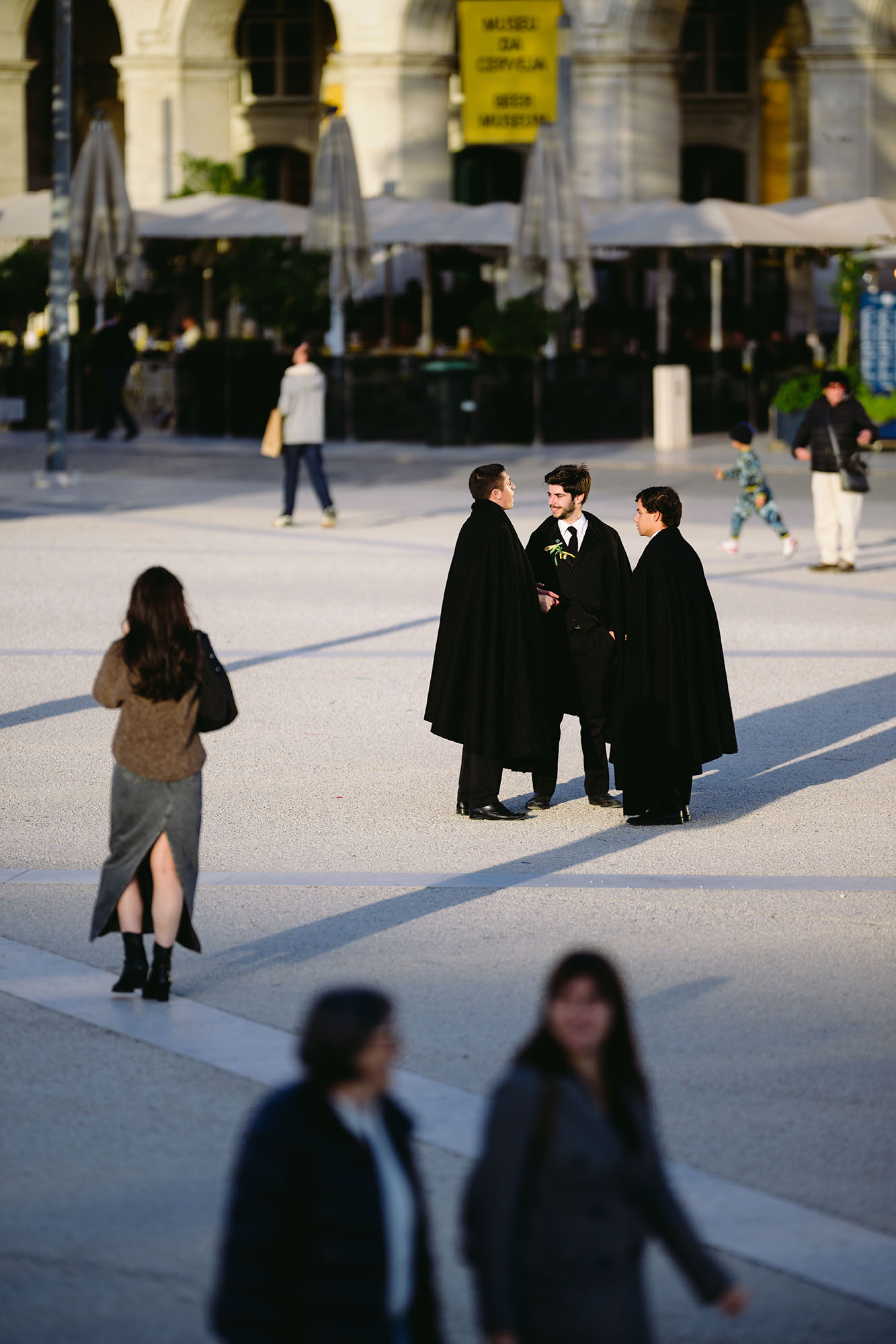 Men in black coats chatting at the Praca do Comercio in central Lisbon, Portugal