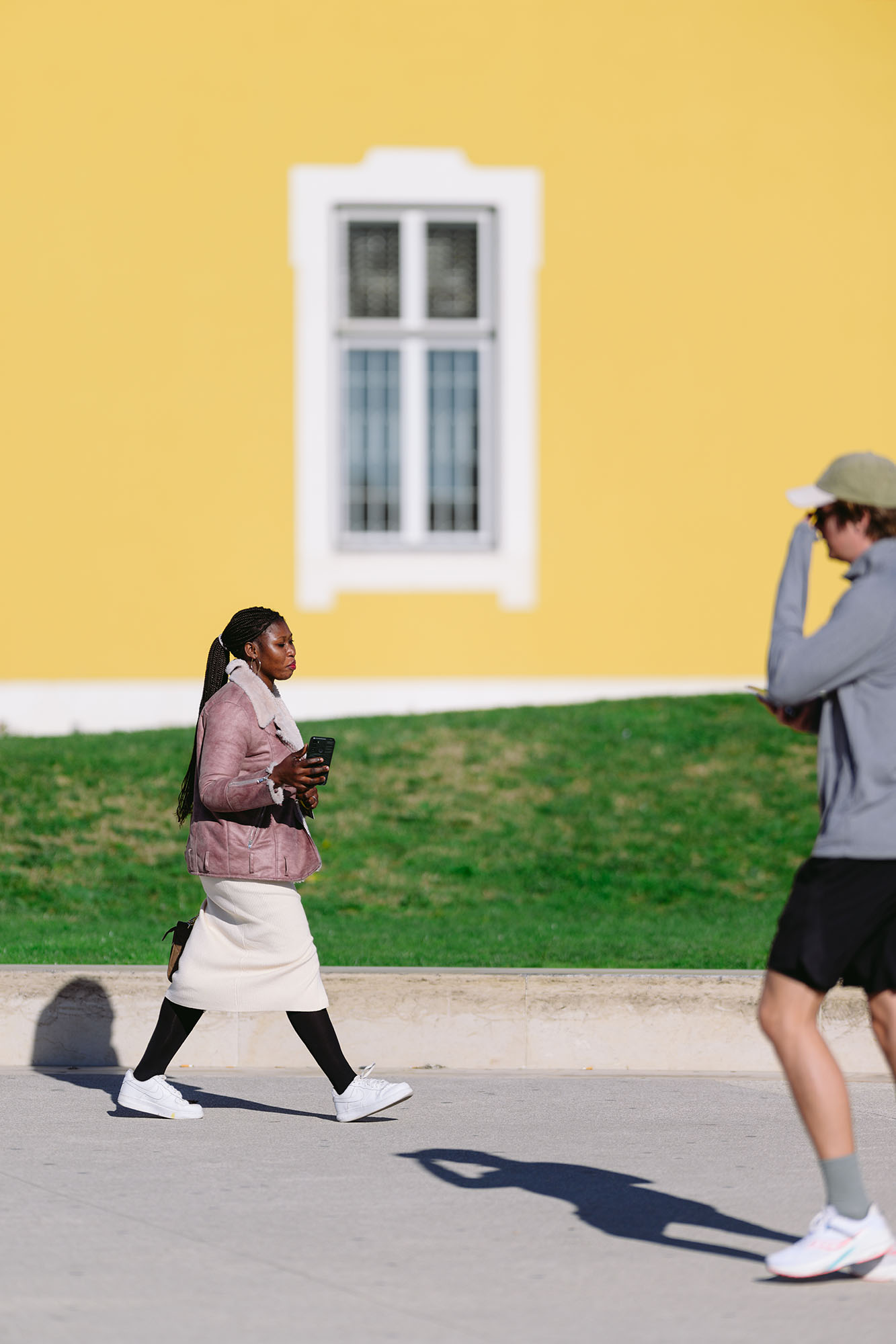 People walking in front of the yellow wall on a sunny day in Lisbon, Portugal