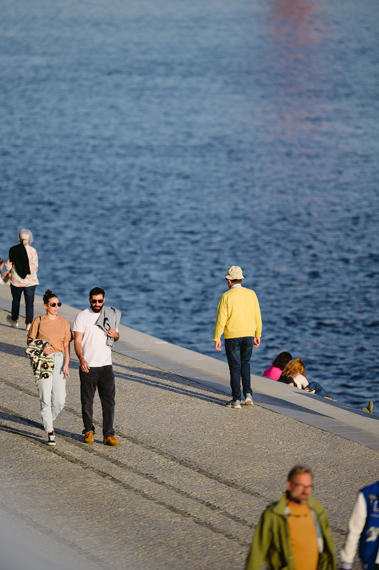Man in yellow sweater walking along the Tagus river in Belem area of Lisbon, Portugal
