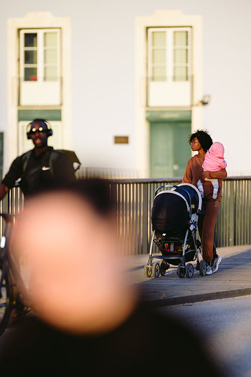 Woman with the child walking in the evening sun along the Tagus river in central Lisbon, Portugal