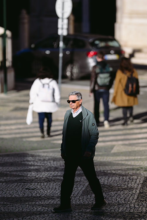 Man in sunglasses crossing the square in front of the Lisbon City Hall just before the sunset