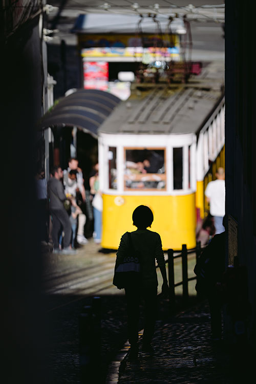 Silhuette of a woman in front of a yellow tram in Principer Real area of Lisbon, Portugal