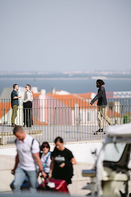 Local skateboarder and tourists at the viewing point in Alfama area of Lisbon, Portugal