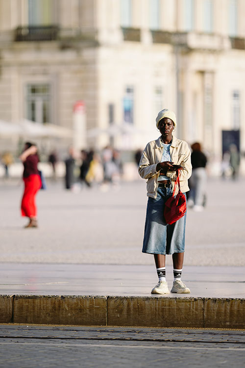 Woman with a red handbag in the evening sun at the Praca do Comercio in central Lisbon, Portugal
